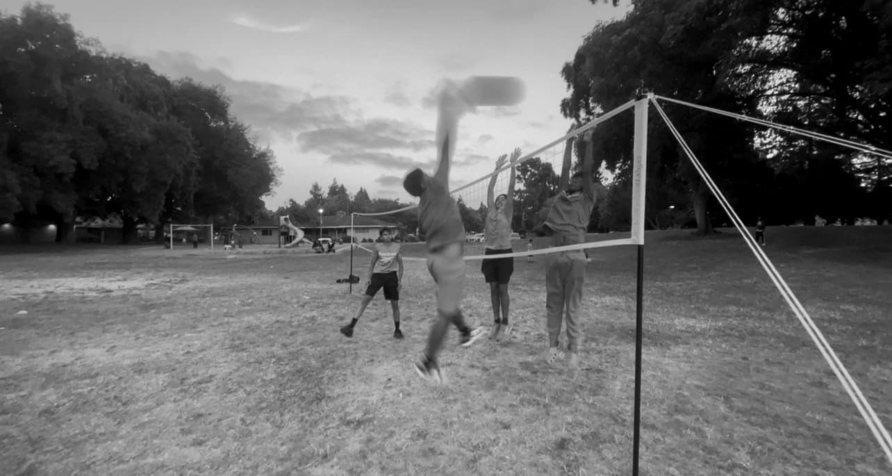Players at the net during an evening volleyball game at a Fremont park
